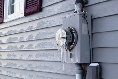 Frozen electrical utility meter on house  exterior siding. clipart