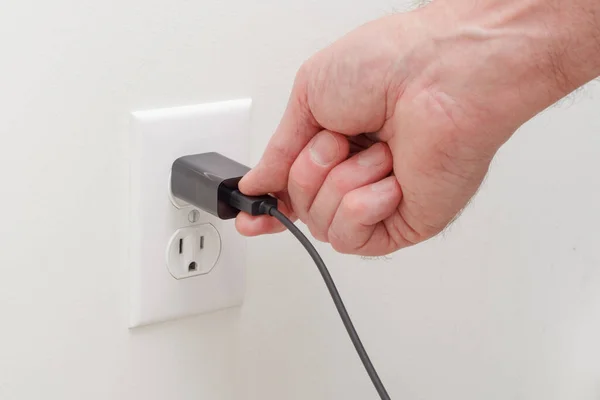 stock image Person connecting usb adapter plug into electrical wall outlet
