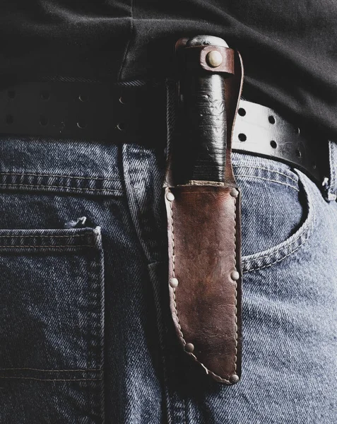 Hunting knife in sheath on jeans belt