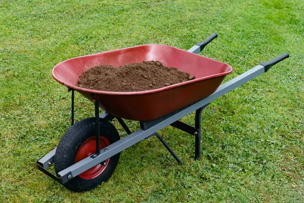 Red wheelbarrow and soil on yard lawn