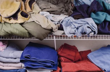 Elbiseler ve havlularla dolu kirli bir çamaşır odası.