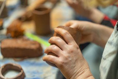 İnsan eli kapalıyken kilden kupa yapmak. Çömlekçilik dersi. Potter tabakları kilden, seramiklerden yapar. El işi, atölyede elle çalışma..