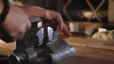 Adam mengeneyle metal parçalarını öğütüyor.
