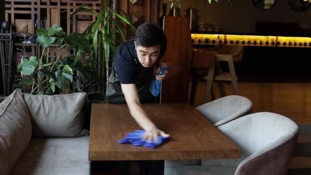 Мужчина Азиатский Официант Тёмной Форме Вытирает Стол Обработанный Моющим Средством — стоковое видео