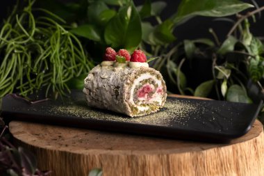 Krem peynirle doldurulmuş, ahududu ve nane yaprağıyla süslenmiş şam fıstıklı rulonun yakın plan fotoğrafı. Tatlı. Yiyecekler. Pastalar.