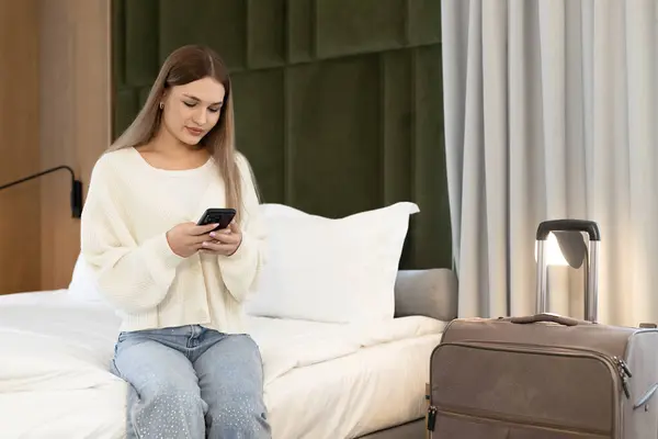 Çekici sarışın kadın yatakta oturmuş internetten bilet alıyor.