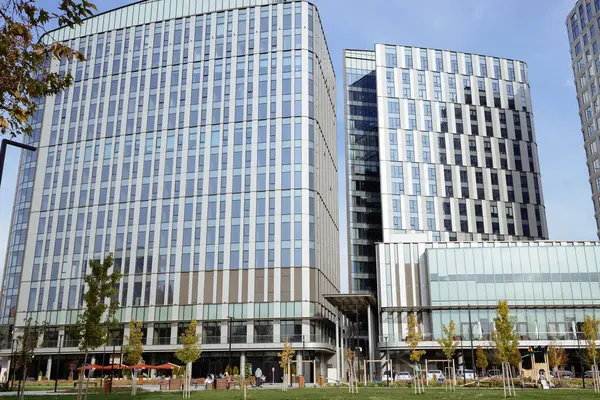 Otoparkı olan yüksek katlı bir ofis binası. Parlak cam gökdelenin ön manzarası. Yansıtıcı pencereli modern ticaret merkezi. Uzun, çağdaş otelin ayna camı..