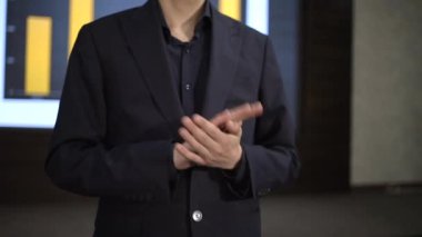 Bir sunum sırasında iş kıyafetlerinde profesyonel jestler yaparak, kurumsal bir ortamda gelecekteki büyümenin kilit başarılarını ve stratejilerini tartışıyor. Adam ellerini çırpıyor.