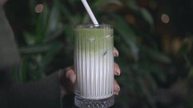 El ele tutuşup güzel katmanlı, limon süslemeli ve içi buz dolu bir süt kokarcasını karıştır. Kadın eli buz karıştırıyor. İkinci içeceği kağıt çubukla karıştırıyor..