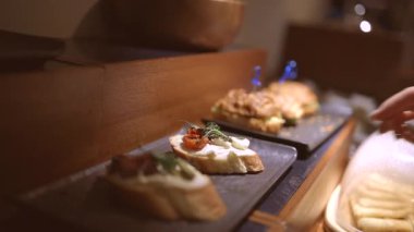 Çeşitli lezzetli aperatifler ahşap tabakta güzelce dizilmiş çeşitli aromalar ve dokular sergileniyor. Bilinmeyen müşterilerin elleri açık büfe sırasında aperatifleri kepçeler..
