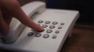 Erkek eli, pansiyon odasındaki ahşap bir masaya yerleştirilmiş beyaz bir sabit hat telefonunda düğmelere basıyor. Telefondaki isimsiz arama numarası. Turist telefonla resepsiyona bağlanıyor.