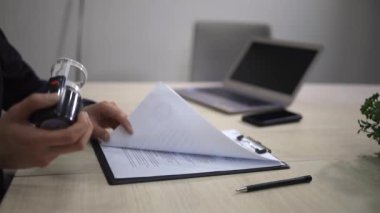 Banka çalışanı mali belgeleri mühürlüyor. Çağdaş ofis ortamında önemli evrakları gözden geçiriyorlar. Ticari belgelere onaylı damga basan bilinmeyen bir adamı kapatın..