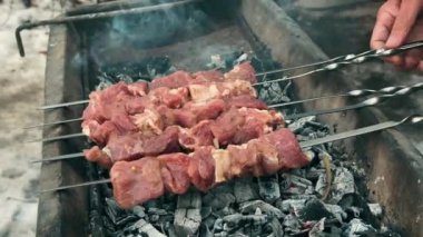 Erkek eller, açık havada yanan kömürün üzerine sulu marine edilmiş eti ustalıkla yerleştirir. Barbekü alevler içinde ızgara yapıyor. İnsan arka bahçede şiş et pişirir. Yemek pişirme konsepti. 