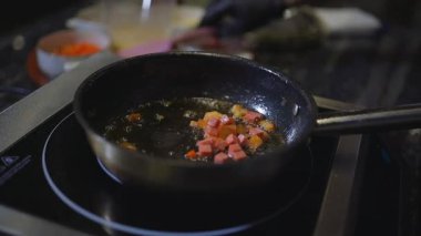 Kızartma tavasında doğranmış sebze ve jambon cızırdıyor. Lezzetli bir koku yaratıyor. Basit ev yemeği teknikleri. Omlet hazırlanıyor..