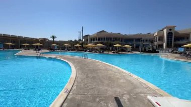 Sharm El Sheikh, Mısır - 13 Mart 2025: Güneşli yaz gününde iki yüzme havuzu arasında küçük bir patikada yürümek. Yaz tatili gezisi konsepti. 