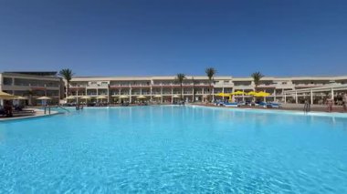 Sharm El Sheikh, Mısır - 13 Mart 2025: güneşli yaz gününde tatil otelinde temiz mavi suyla yüzme havuzu. 