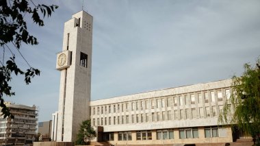 Bişkek, Kırgızistan - 15 Mayıs 2025: Merkezi saat kulesi, gün ortasında açık gökyüzü altında mimari tasarımını sergileyerek modern binalar arasında belirgin bir şekilde duruyor. Kırgız simgeleri konsepti.