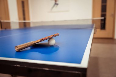 Bishkek, Kırgızistan - 21 Mayıs 2025: Raket ve topla birlikte spor kulübünde masa tenisi masası. Tenis raketi ve top masa yüzeyinde. Spor malzemeleri konsepti.