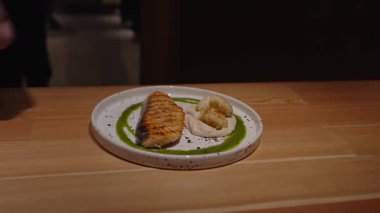 Mükemmel ızgara somon bifteği, kremalı püre ve canlı yeşil sosla tamamlanmış güzel tabaklar. Güzel yemek tecrübesi. Şef alabalık bifteği dekore ediyor..