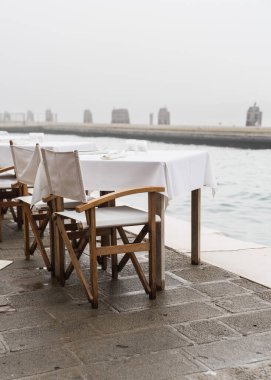 İtalya, Venedik 'te sisli bir günde açık hava restoran masaları