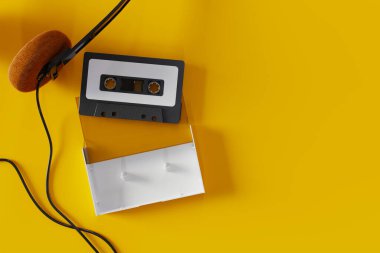 Top view of an old cassette tape and headphones on a yellow background, 3d rendering