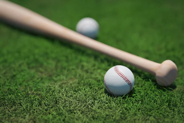 Beyzbol topu ve çimlerin üzerinde beyzbol sopası olan bir arka plan.