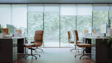 Ofiste, pencerenin dışındaki ormanı görebilen karanlık tonlu, modern bir iç tasarım.