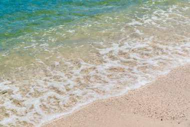 Yaz kumsalı kumu, mavi dalgalar ve beyaz köpük