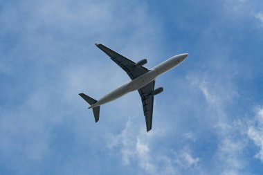 Commercial airplane with contrails from the wingtips flying in a clear blue sky.