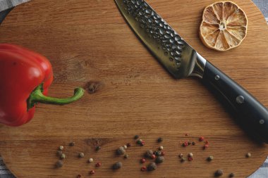 Tamam geçmiş, ev yemeği konsepti. Kırmızı dolmalık biber, şef bıçağı, ahşap arka planda baharatlar, üst manzara, kopyalama alanı. Yemek hazırlama kavramı.