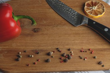 Tamam geçmiş, ev yemeği konsepti. Kırmızı dolmalık biber, şef bıçağı, ahşap arka planda baharatlar, üst manzara, kopyalama alanı. Yemek hazırlama kavramı.