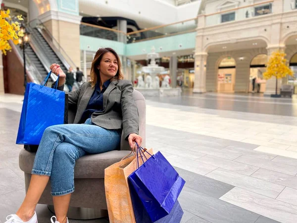 Joyful Bela Fêmea Sentada Cadeira Shopping Center Com Muitos Sacos — Fotografia de Stock