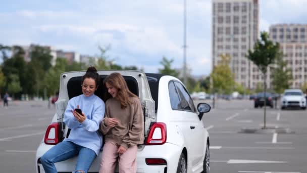 Genç Bir Kızla Arabanın Bagajında Oturan Neşeli Genç Bir Kadın — Stok video