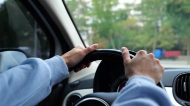 Kadın ellerinin şehirde pratik yaptığı direksiyon simidini kapat. Kadın sürücü ellerini direksiyona koyup park alanında sola dönüyor. Ağır çekim. Sürücü başlatıcısı