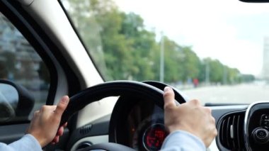 Kapatın. Arabanın içindeki görüntüler. Direksiyondaki kadın elleri direksiyonda. Kadın elleri direksiyonu çeviriyor, şehirde sağa dönüyor. Ağır çekim. Ehliyet sınavı. Sürücü başlatıcısı