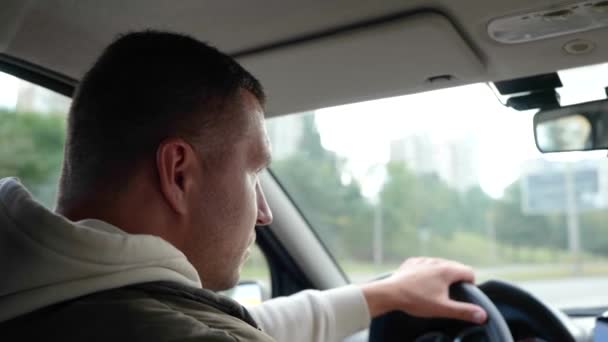 英俊的白人成年男子开车在高速公路上 一边看一边看 后视镜靠近点男子手牵着方向盘在城市开车 驾驶汽车 慢动作 — 图库视频影像