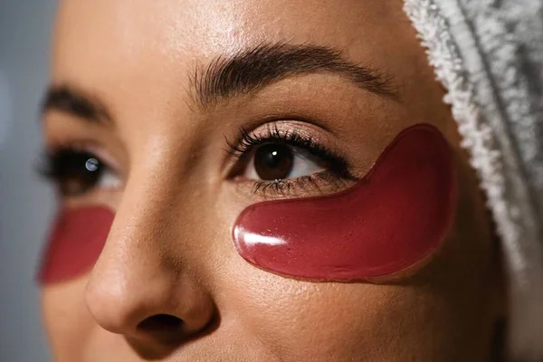 Extreme close up of gel eye patches on female face. Beautiful young Caucasian woman with eye patches on face. Skincare product concept. Home beauty routine. Cosmetics and beauty products