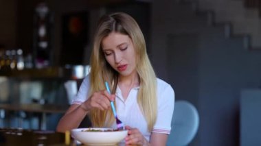 Close up portrait of pretty young blonde woman eating in restaurant alone in good mood. Caucasian joyful female having lunch or supper in cafe. Leisure. Luxury lifestyle. Real time. . Food concept