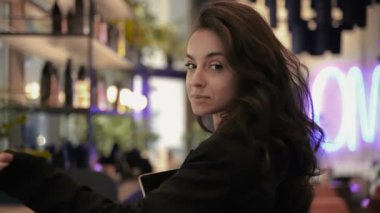 Kafkasyalı bir kadın restoranda hostes olarak çalışıyor, kız siyah ceket ve beyaz gömlek giyiyor, kafede dolaşıyor ve kamerayla konuşuyor..