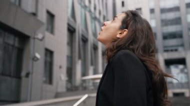 Genç beyaz kadın büyük şehirde yürüyor, etrafa bakıyor, şehir merkezindeki büyük çağdaş binalara hayran. Şehir merkezinde yürüyen uzun saçlı bir kadın ve bir kız gülümsüyor..