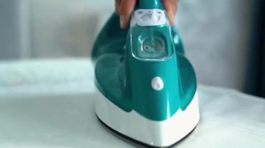 Yakın çekim, gerçek zamanlı video, uzaklaşma, beyaz bir kız kırmızı seksi iç çamaşırı giyiyor ve nazikçe ütü yapıyor. Yeşil ütü, ütü masasındaki temiz giysileri ütülüyor..