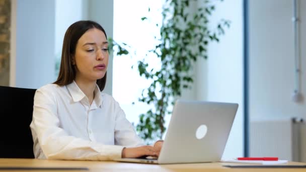 スローモーションビデオ 白いシャツの暗い長い髪を持つ美しい白人女性は コンピュータの前に座っている 仕事や動揺を探しています 女性は現代的なオフィスで働いていると疲れて見て — ストック動画