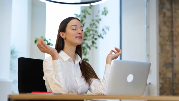 白いシャツに黒い長い髪をした白人の若い女性は 長時間労働した後 コンピュータの前で瞑想しています 仕事中にテーブルに座ってリラックスしているビジネス女性 — ストック動画
