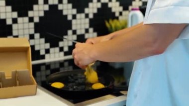 Kafkas asıllı genç ve çekici bir kadın evde yumurta pişiriyor. İç çamaşırlı ve beyaz bornozlu seksi bayan mutfakta kahvaltı hazırlıyor. Yemek hazırlama. Gerçek zamanlı..