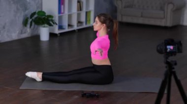 Spor yapan ve vücudunu esneten sporcu kadının yan görüntüsü, evde yerde otururken egzersiz yapmadan önce kaslarını ısıtması. vlog için kadın spor kaydı videosu