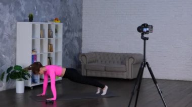 Spor yapan genç bayan evde oturma odasında spor yapıyor. Burpee yapıyor, antrenman yapıyor ve fonksiyonel egzersiz yapıyor. vlog için kadın spor kaydı videosu