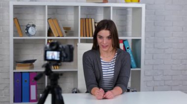 Çekici beyaz kadın video blogcu kameraya bakıyor ve teknoloji ile video çekiminde konuşuyor. Neşeli kadın evde video kaydediyor. Günlük konsepti
