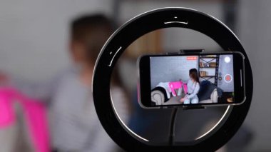 Gülümseyen beyaz blogcu kadın kameraya kıyafetlerini gösterip bir gün için bakmayı seçiyor. Kadın cep telefonuyla video kaydediyor. Yavaş çekim videosu