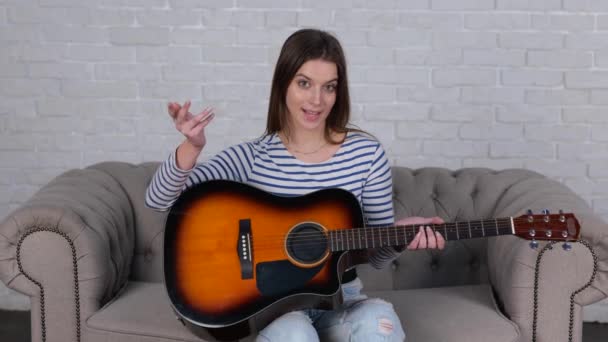 Gülümseyen Eğlenen Gitar Çalarak Şarkı Söyleyen Evdeki Kanepede Oturup Kameraya — Stok video
