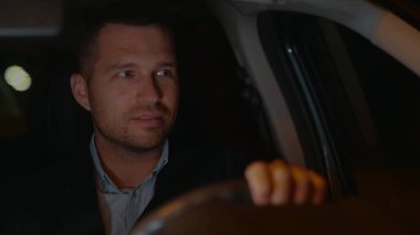 Arabanın içinde takım elbiseli yakışıklı, neşeli genç adama yaklaş. Başarılı bir iş adamı geceleri yola bakarak otomobilini sürüyor. İş gezisi. Olumlu duygular. Seyahat kavramı